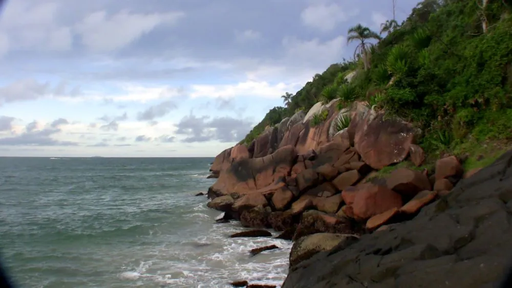 A rocky point on the coast of Florianópolis island, with waves breaking on the rocks